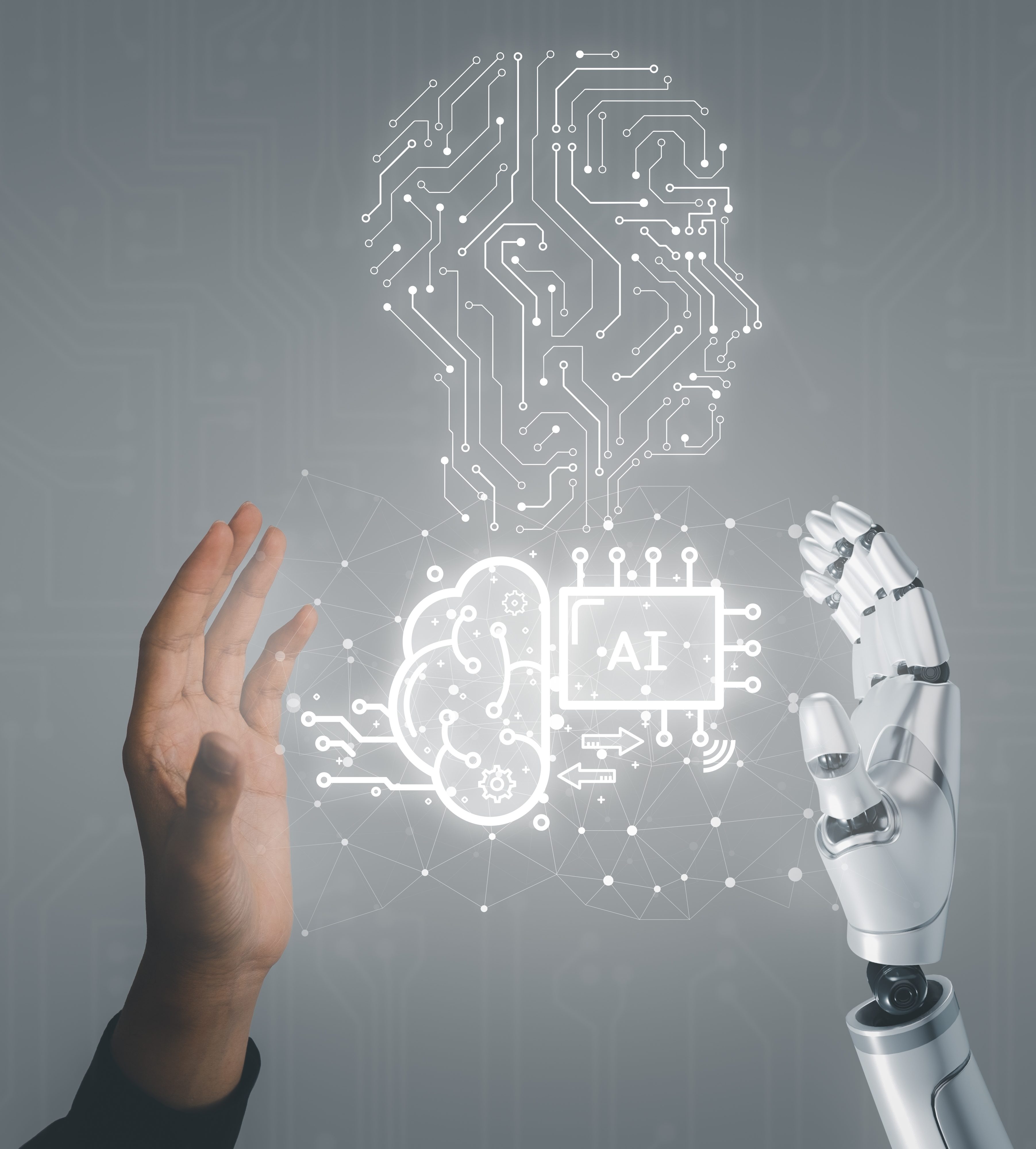 A human hand reaching towards a robotic hand, with a graphic representation of a brain and AI circuitry in the background.